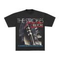 A black short-sleeve graphic T-shirt featuring 'The Strokes' album artwork for 'New York' from October 24, 1986, with 'Flushing Meadows Corona Park' text at the bottom, shown on a plain white background.