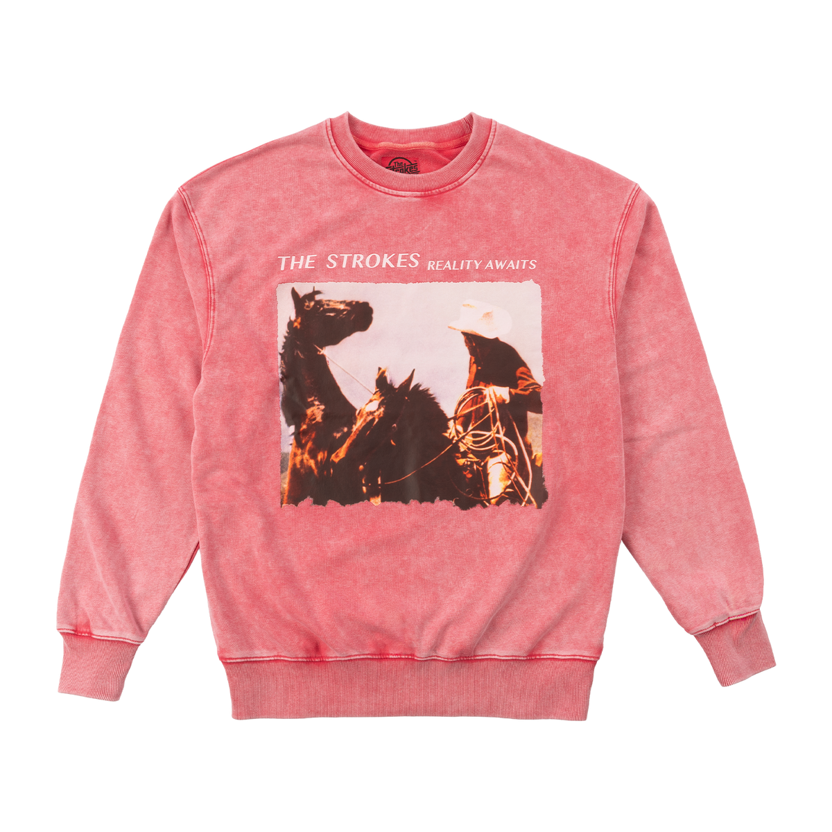 A bright pink crewneck sweatshirt featuring a front graphic print of The Strokes' 'Reality Awaits' album artwork with a cowboy on horseback.