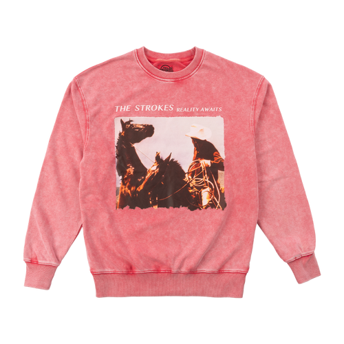 A bright pink crewneck sweatshirt featuring a front graphic print of The Strokes' 'Reality Awaits' album artwork with a cowboy on horseback.